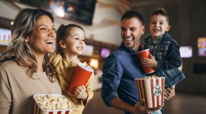 Young happy family with popcorn and drinks in movie theatre